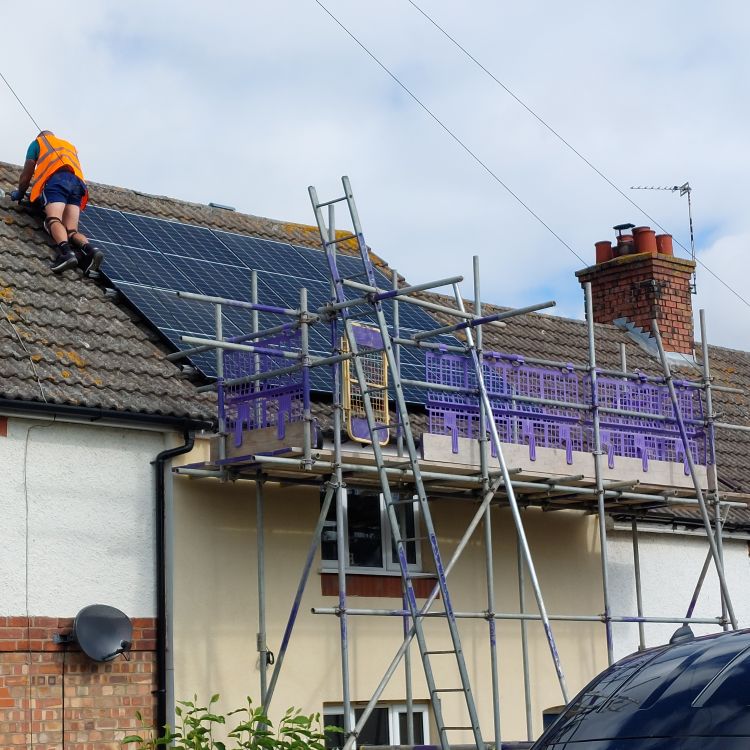 Solar PV panels being fitted on house with scaffolding in place