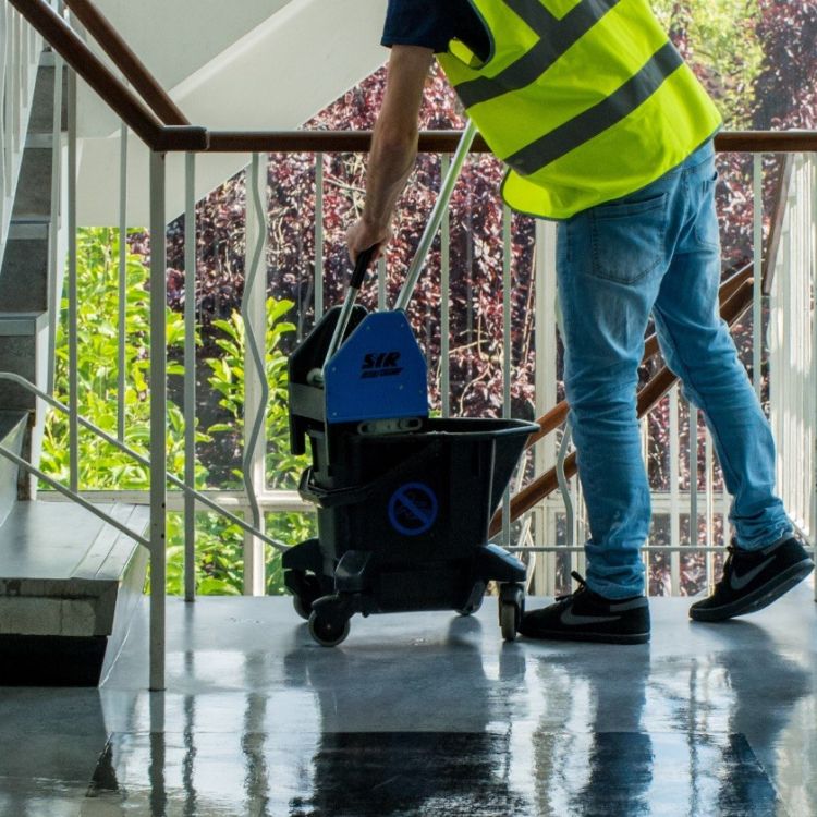 Male in a high-vis vest mopping a staircase floor