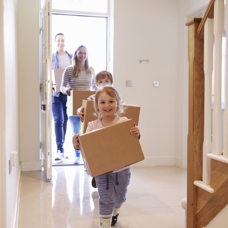 Family Carrying Boxes Moving Into their New Home