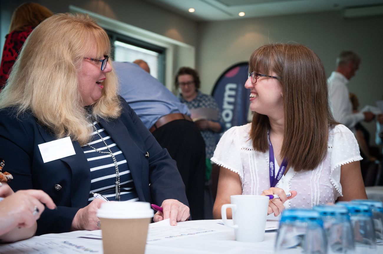 Two ladies talking to each other and smiling